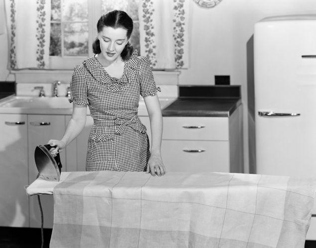 Woman ironing in the kitchen, c 1940s.